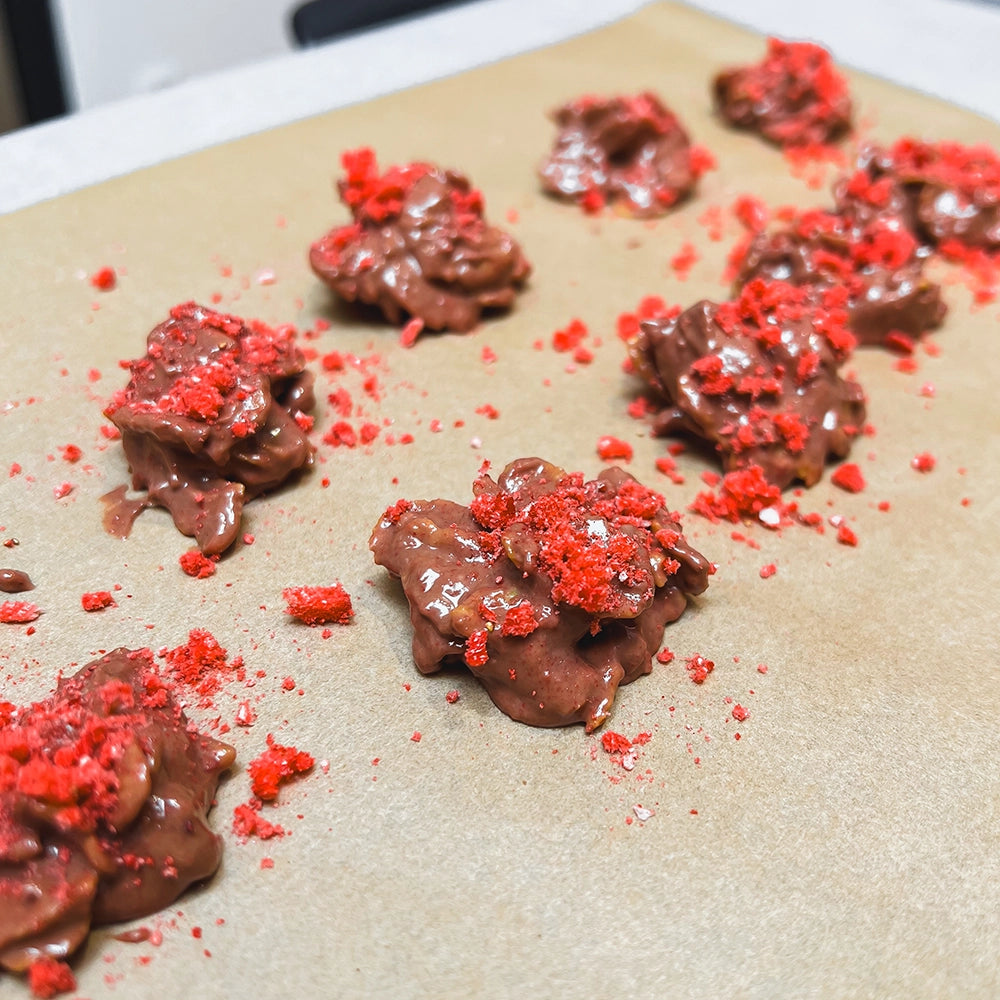 Nahaufnahme von den Schoko-Crossies mit gefriergetrockneten Erdbeeren von FRUDIST auf Backpapier